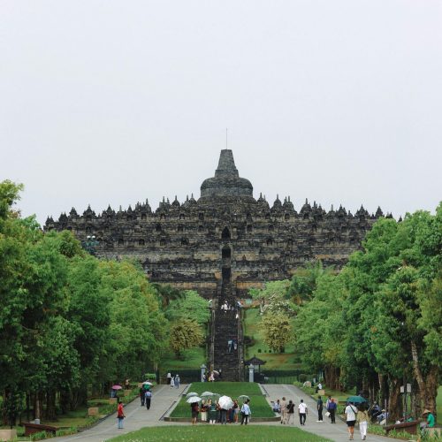 People visiting the iconic Borobudur Temple in Central Java, Indonesia, on a cloudy day.